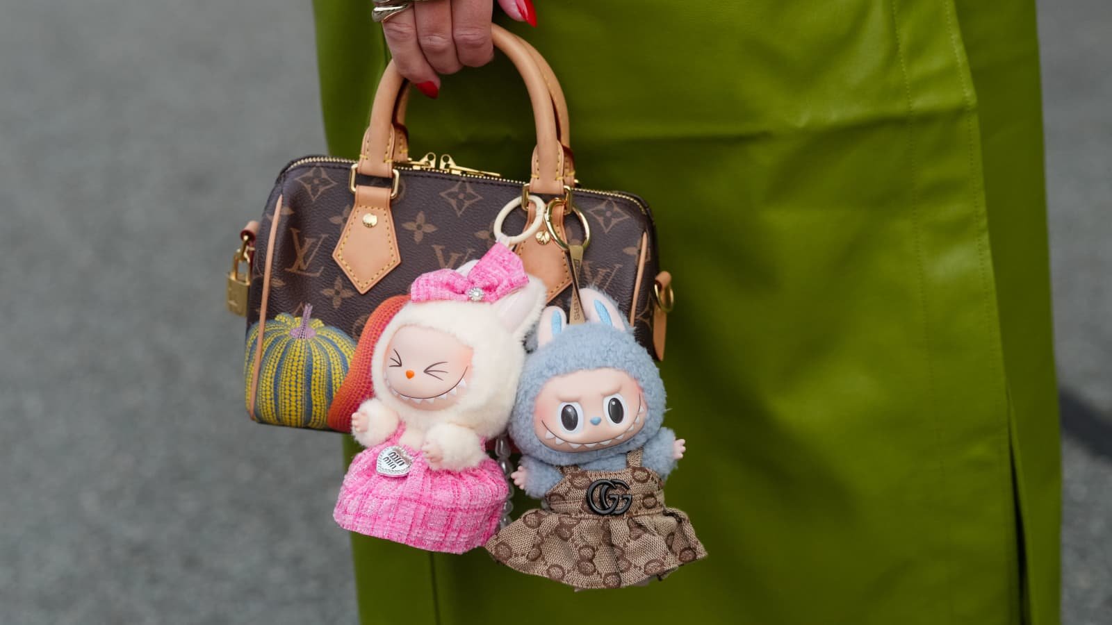 Labubu doll wearing a luxury-inspired outfit, acting as a high-value bag charm on a designer handbag.